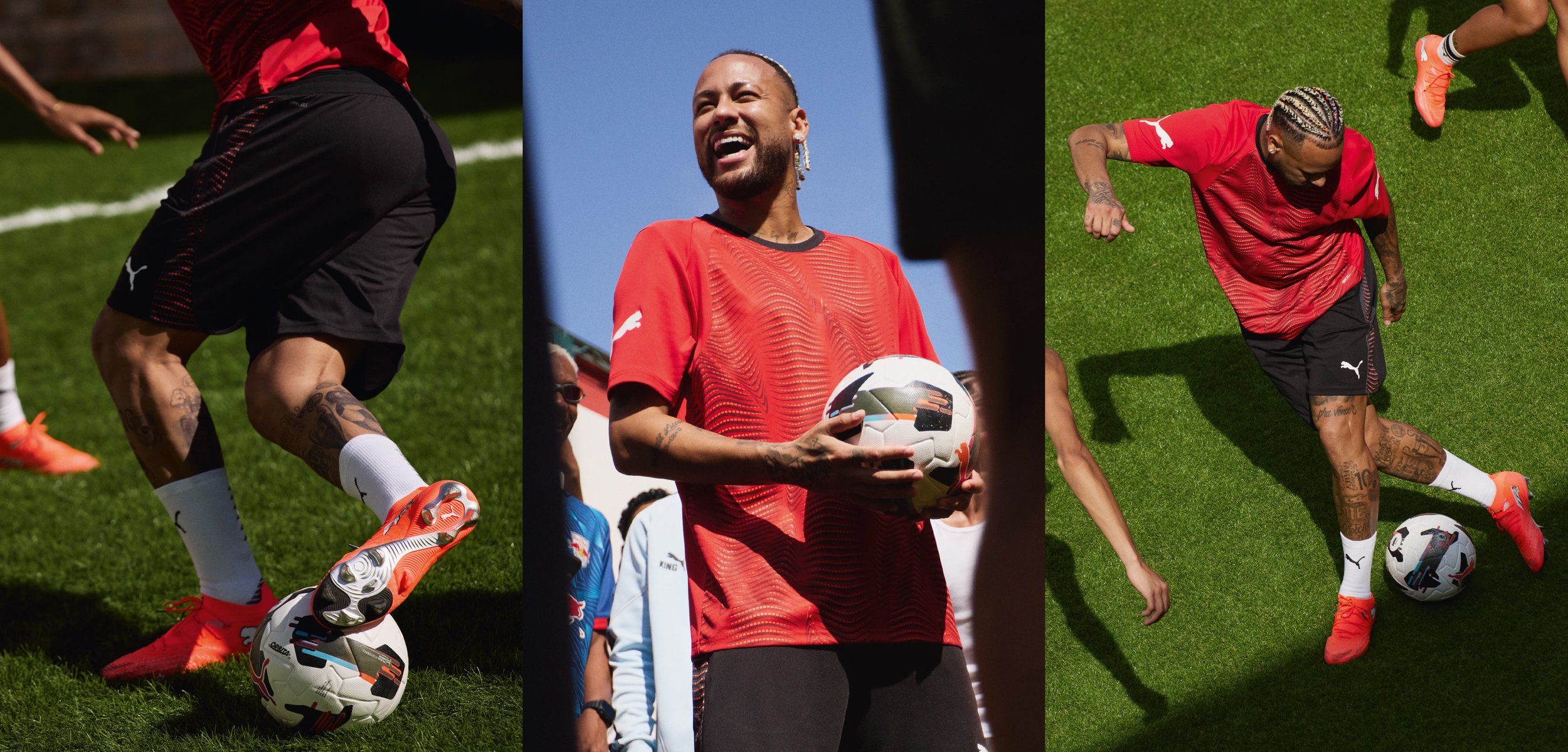 Piros ingben és fekete rövidnadrágban lévő futballjátékos labdát vezet és tart zöld fűben napsütéses napon.