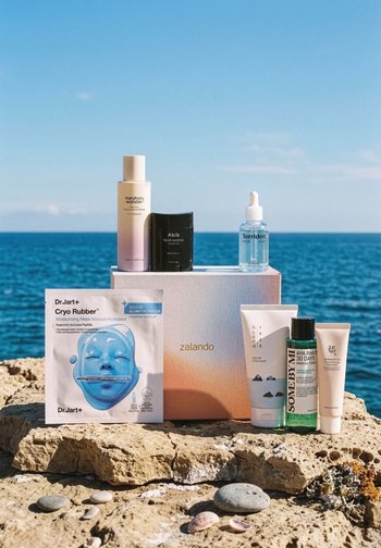 Seven skincare products on a stone surface by the sea, including a Dr.Jart+ Cryo Rubber mask and a Zalando branded box.