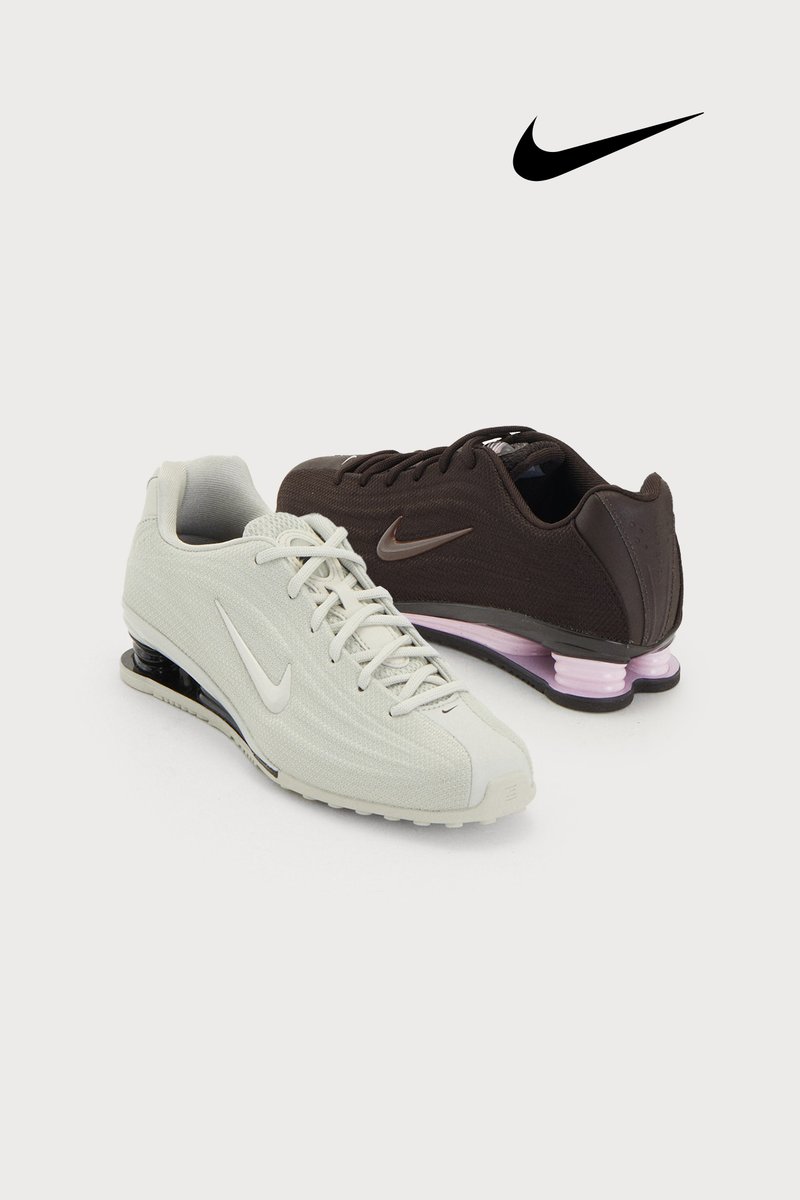 Nike sportssko i lysegrå og mørkebrun med tekstureret stof, snørebånd, polstrede såler med synlige luftenheder og logo-detaljer.