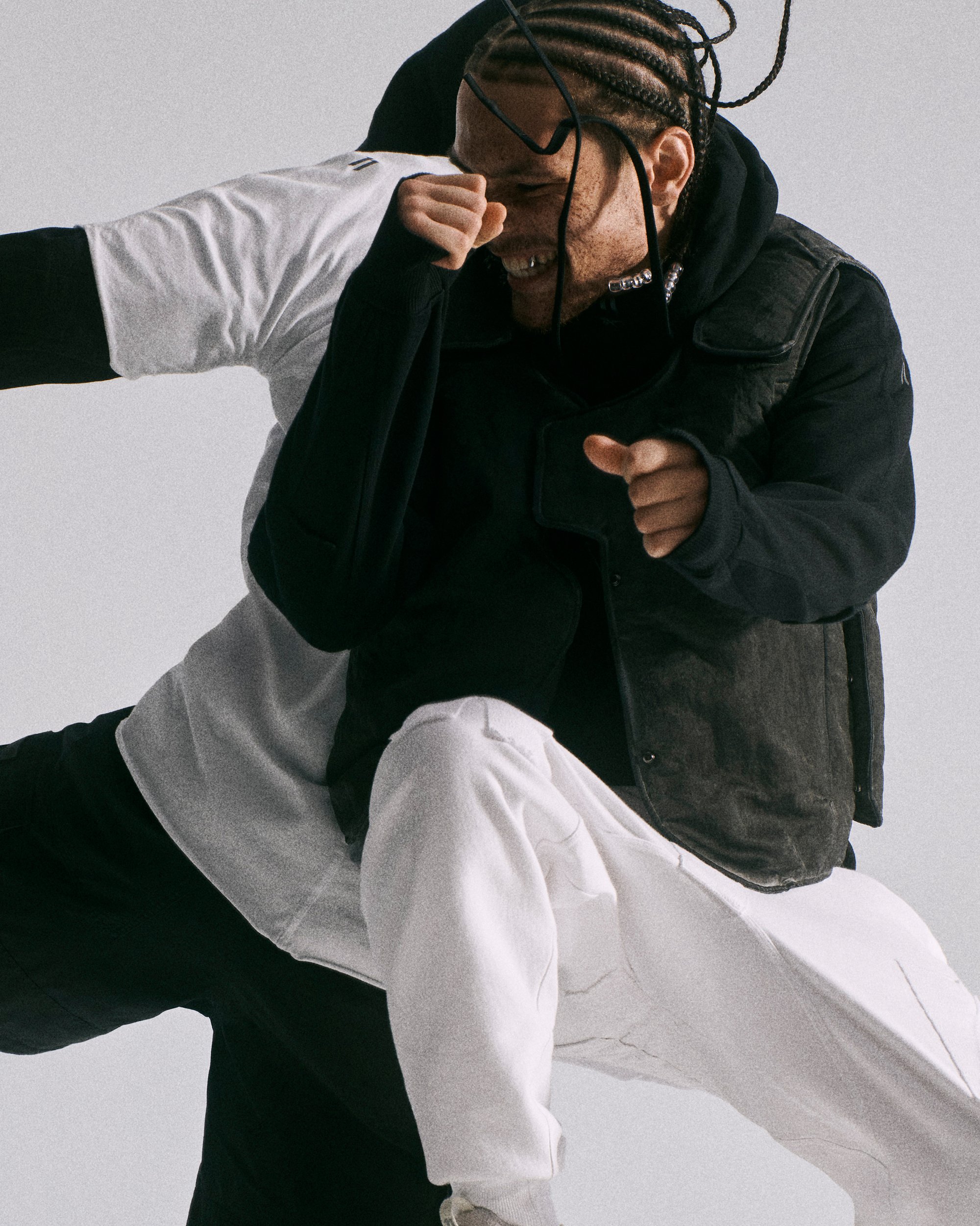 Two individuals in dynamic poses engage in a playful dance or performance. One wears a dark vest over a black shirt, the other in a white top.