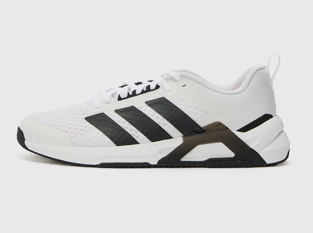 Witte sportschoen met drie zwarte strepen, zwarte hielondersteuning, witte veters en een gestructureerde zool, gezien vanaf de zijkant.