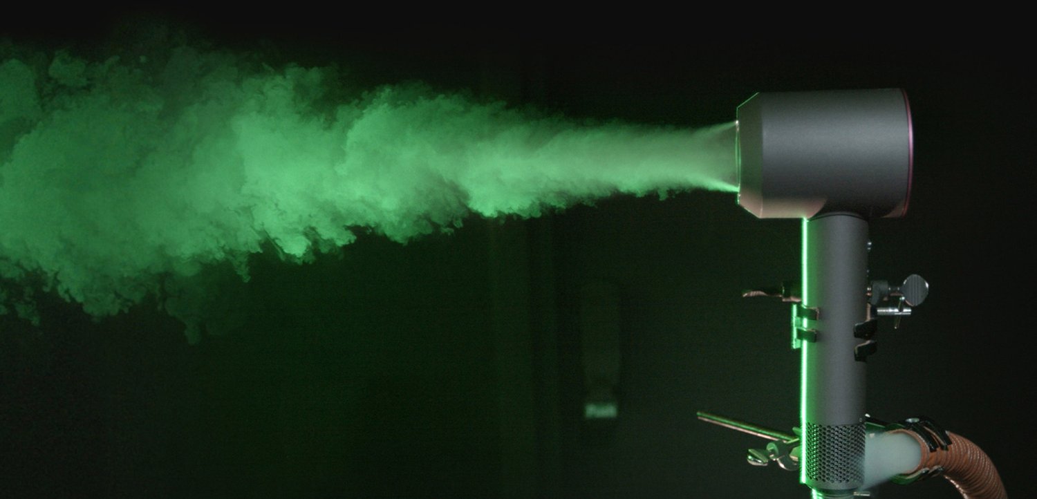 Groene rookmachine met een cilindrische zwarte behuizing, die felgroene rook uitstoot. Voorzien van een gewatteerde grip en meerdere instelknoppen.