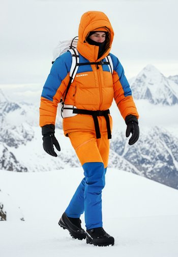 Φωτεινό πορτοκαλί και μπλε μονωμένο μπουφάν με κουκούλα, συνδυασμένο με αντίστοιχο παντελόνι, γάντια και μαύρες χειμερινές μπότες. Φόντο με χιονισμένα βουνά.