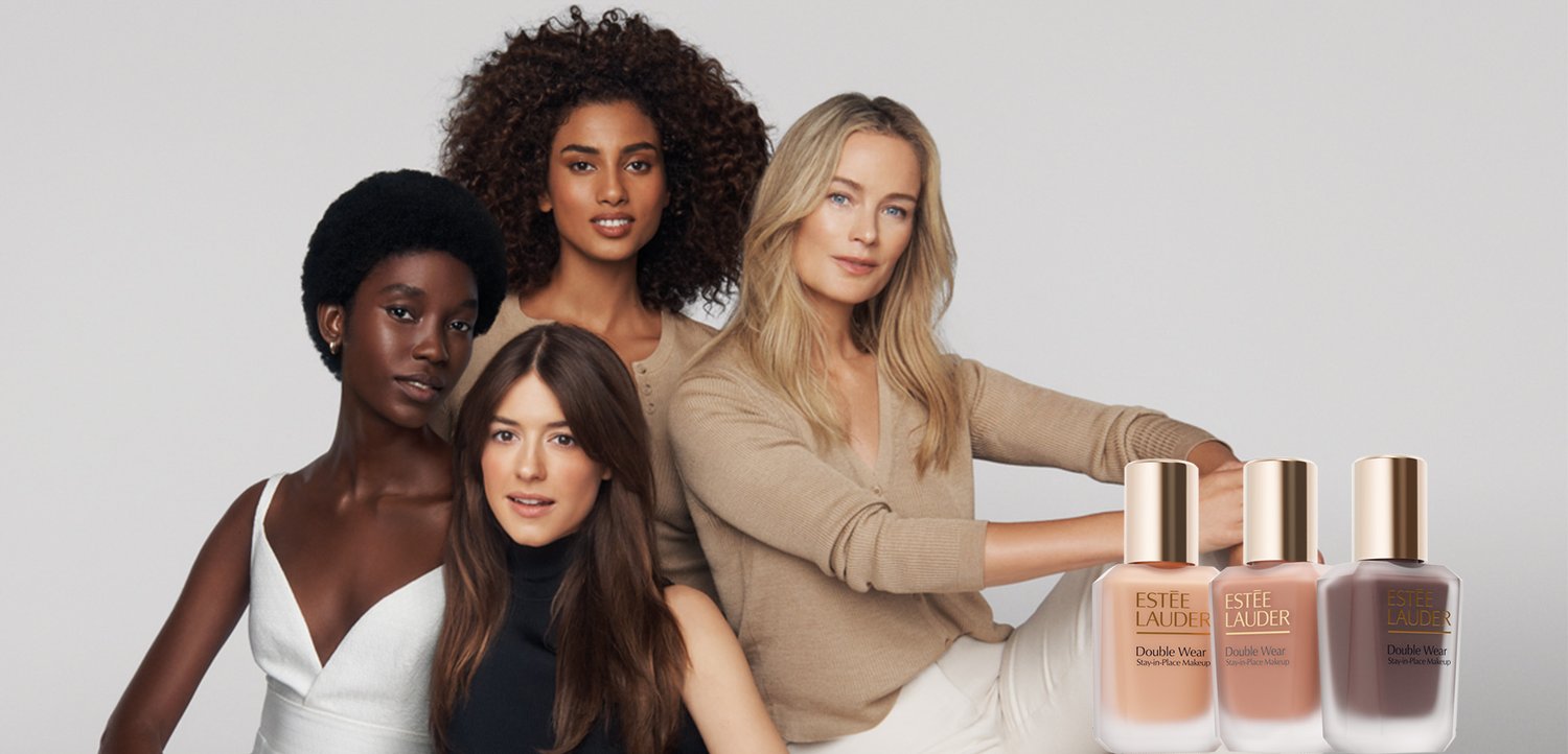 Vier verschiedene Frauen mit unterschiedlichen Hauttönen posieren neben drei Farbtönen der Estée Lauder Double Wear Foundation-Flaschen.