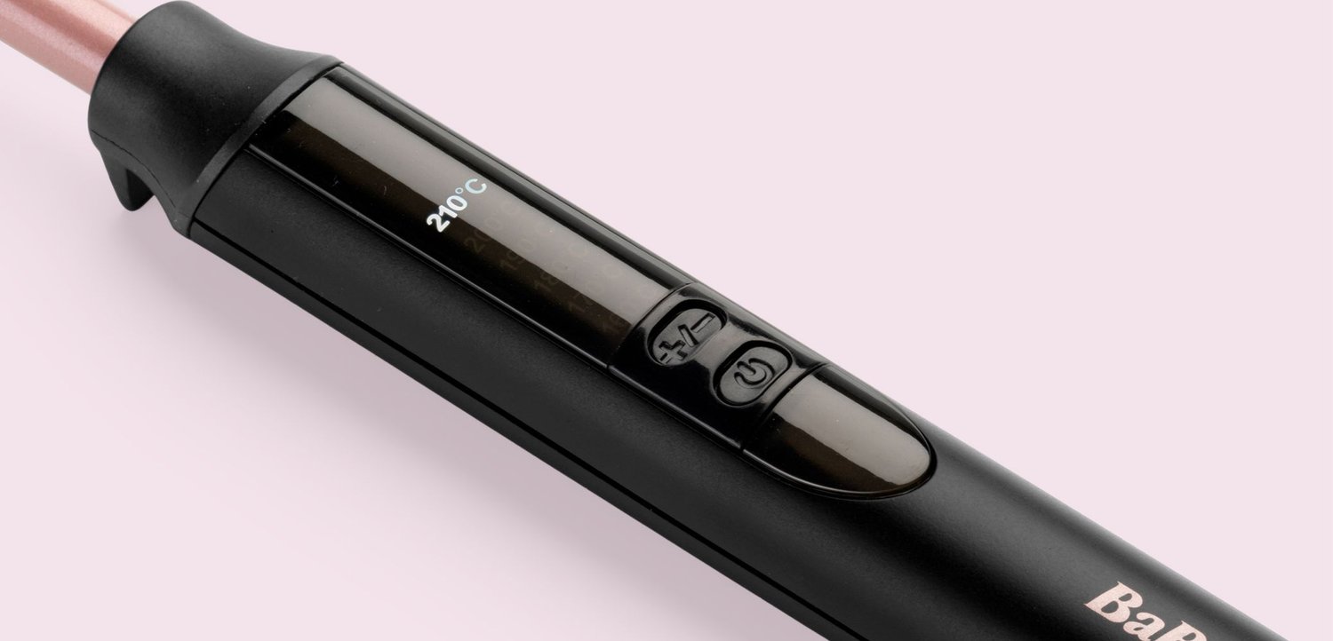 Close-up van een zwart en roze handvat van een stijltang met temperatuurregelknoppen en een digitaal display dat 210°C aangeeft.