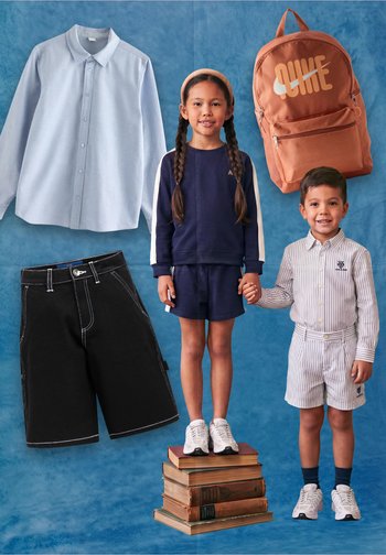 Due bambini si tengono per mano; la bambina con un abito blu navy sta in piedi sopra dei libri, il bambino con una maglietta a righe e pantaloncini, con una maglietta blu, pantaloncini neri e uno zaino arancione vicino.