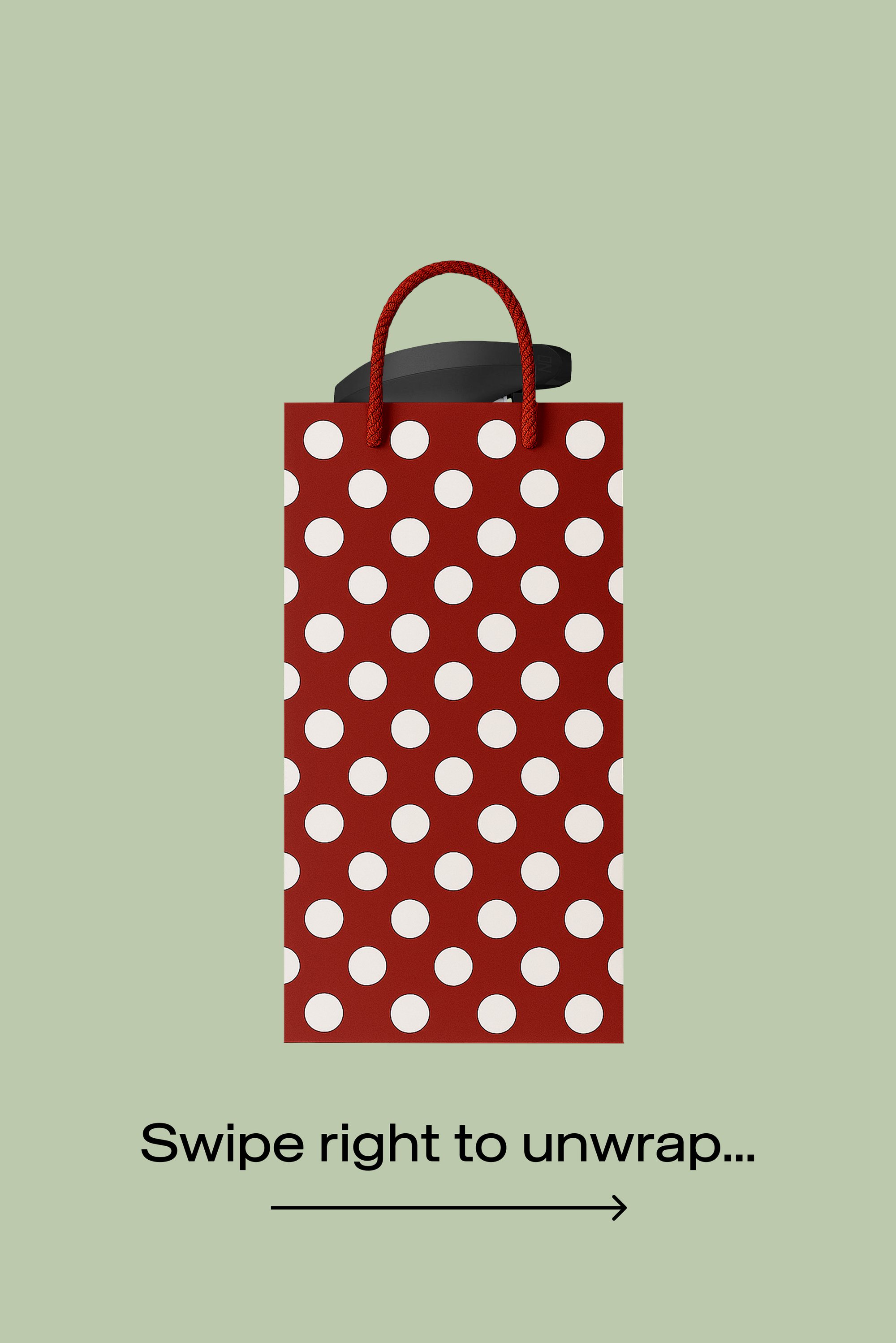 Borsa di carta rossa con pois bianchi, caratterizzata da una finitura texturizzata e robuste maniglie in corda rossa. Dettagli neri nella parte superiore per una presa migliore.