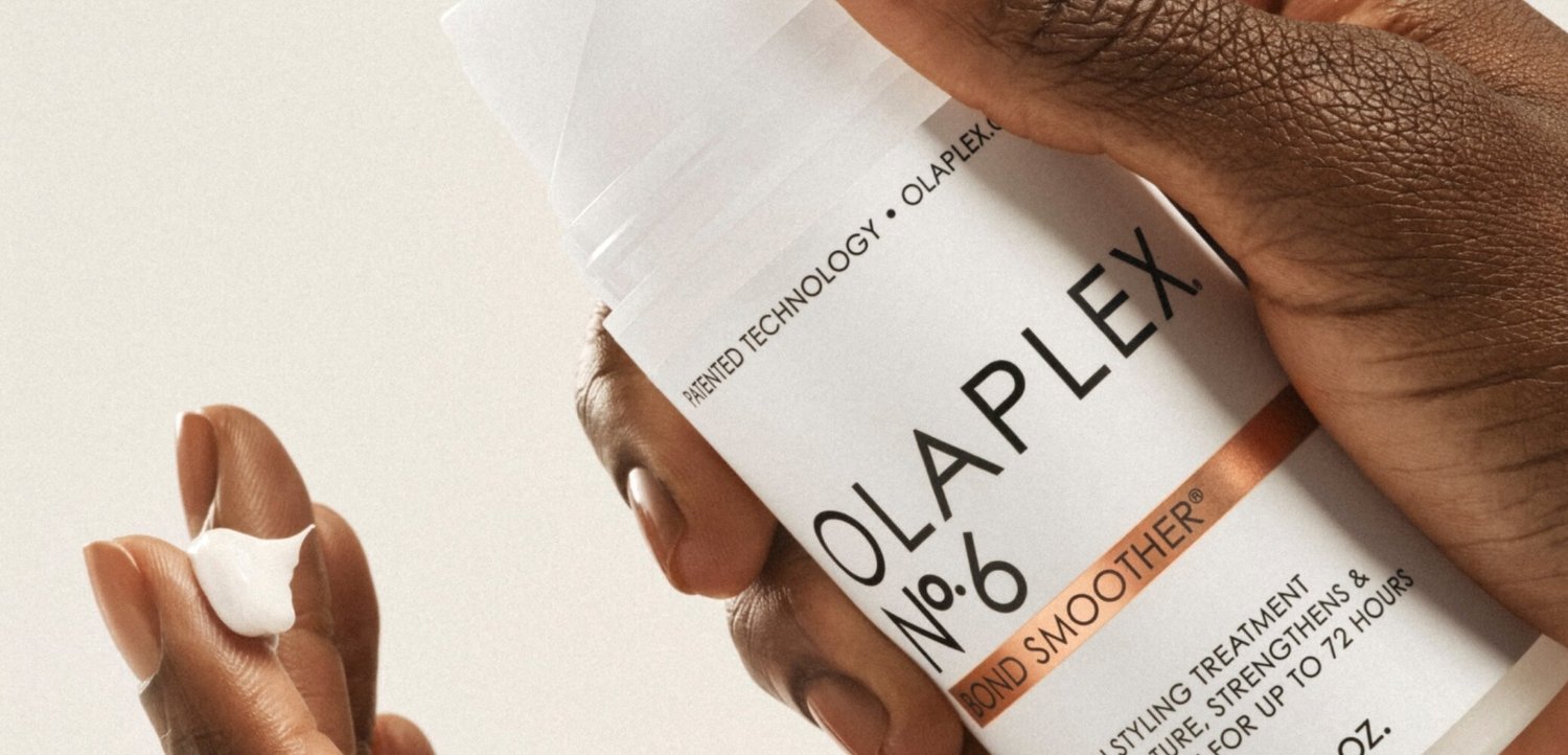 Ręka trzymająca Olaplex No. 6 Bond Smoother – zabieg do stylizacji włosów z kremem na czubku palca.