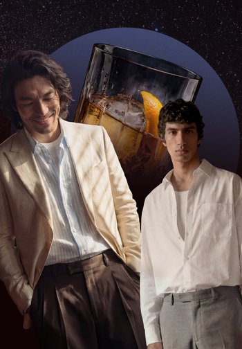 Δύο άντρες με λευκά, καθημερινά πουκάμισα και σακάκια στέκονται μπροστά από ένα μεγάλο ποτήρι παγωμένου ποτού με φλούδα πορτοκαλιού, σε φόντο ένα αστροφεγγές νυχτερινό ουρανό.