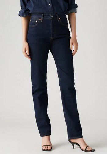 Mørkeblå høyt liv jeans med slank passform, rette ben, kobber detaljer og en subtil tekstur. Kombinert med svarte hæler.