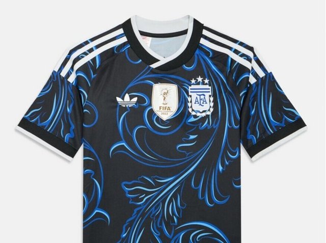 Fekete-kék argentin focimez fehér Adidas csíkokkal, a FIFA 2022-es győztesek jelvényével és az AFA címerével, melyen három csillag van.