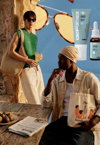 Deux hommes avec des sacs fourre-tout près d'une table en bois avec des figues et un journal, de grandes lunettes de soleil et des produits de soin de la peau en arrière-plan.