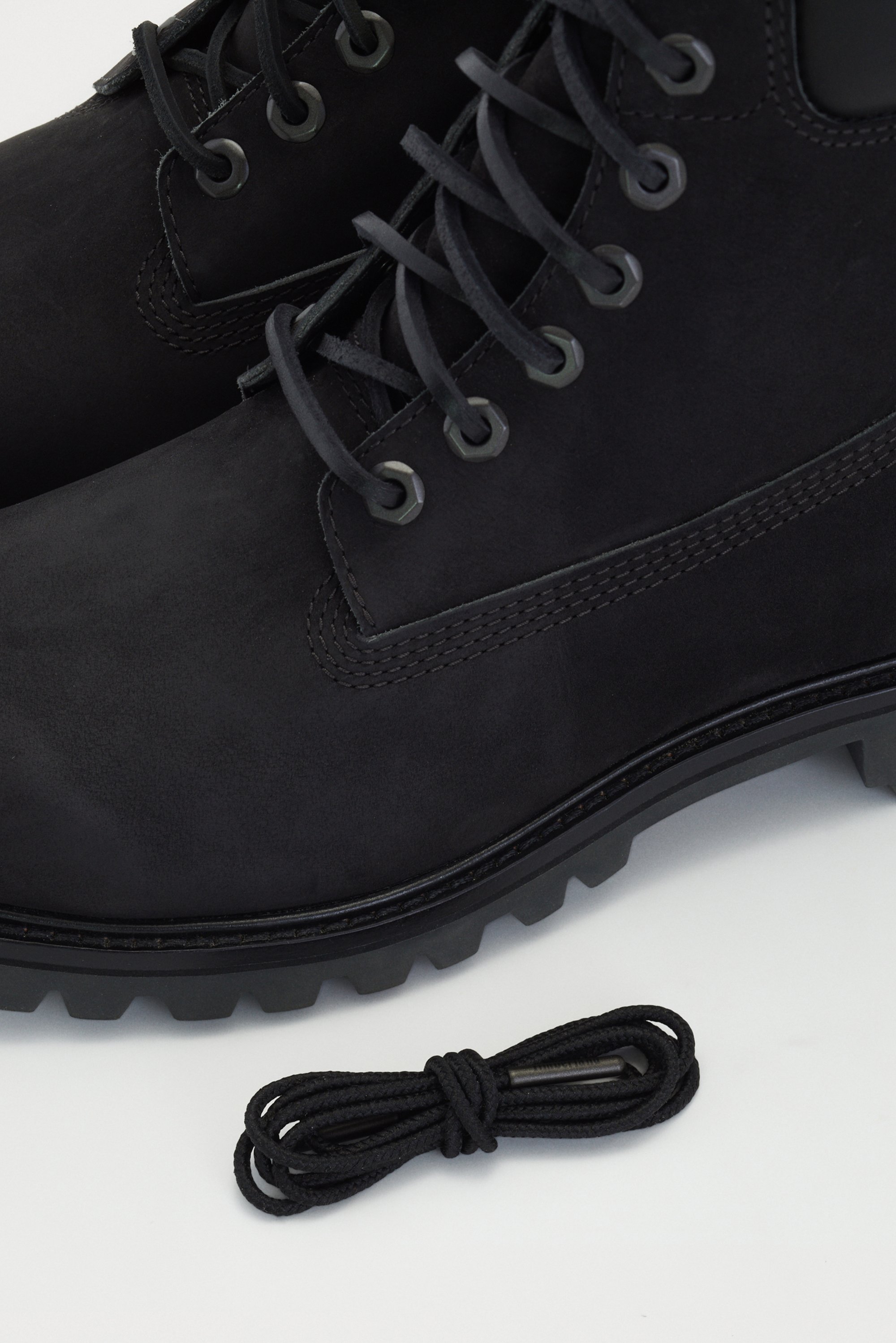 Black leather ankle boots with a round toe, thick treaded sole, and metal eyelets. Comes with a matching black shoelace.