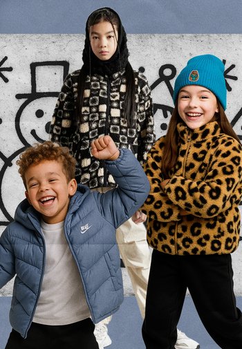 Drei Kinder tragen bunte Oberbekleidung: eine schwarz-weiße karierte Fleecejacke, ein Fleecepullover mit Leopardenmuster und eine blaue Steppjacke.
