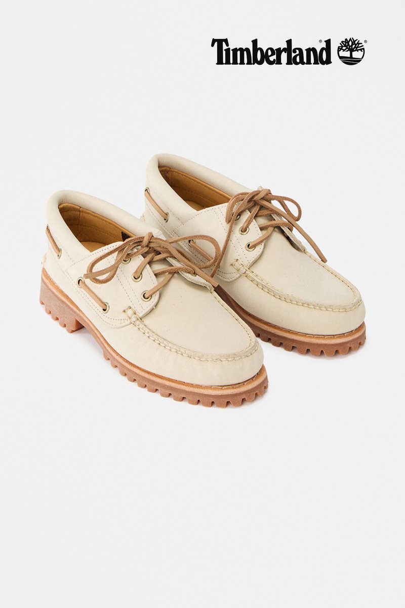 Chaussures bateau Timberland en cuir beige avec des lacets marron et des semelles en caoutchouc robustes couleur tan, présentées côte à côte sur un fond blanc.