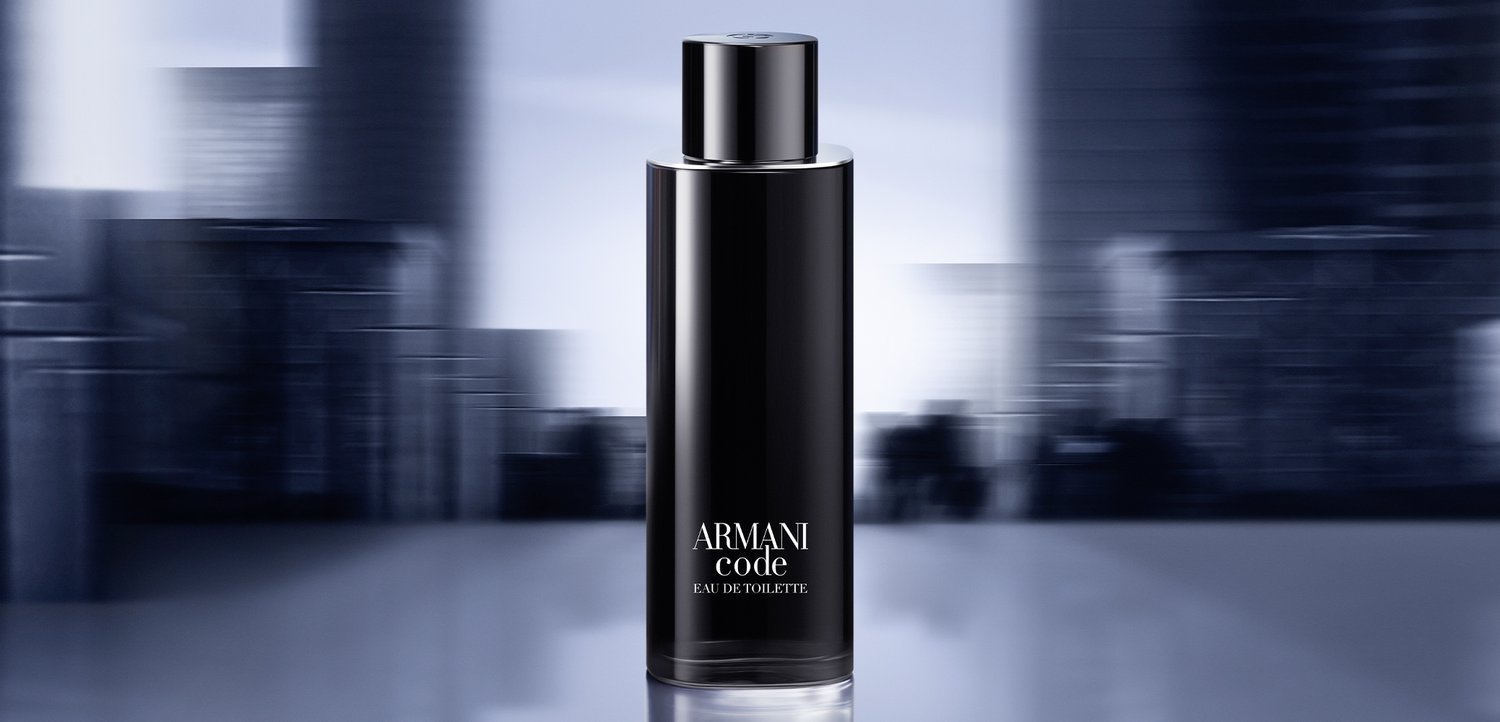Flacon noir cylindrique Armani Code Eau de Toilette centré sur un fond de paysage urbain bleu flou.