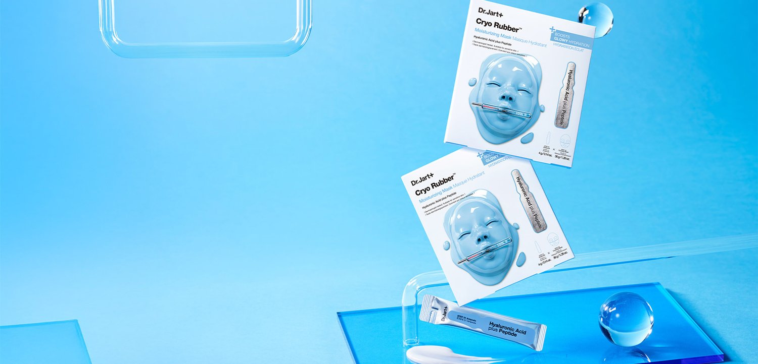Deux masques hydratants Dr.Jart+ Cryo Rubber avec un design de visage bleu, un tube de duo repulpant à l'acide hyaluronique, et des sphères transparentes sur une surface bleue.