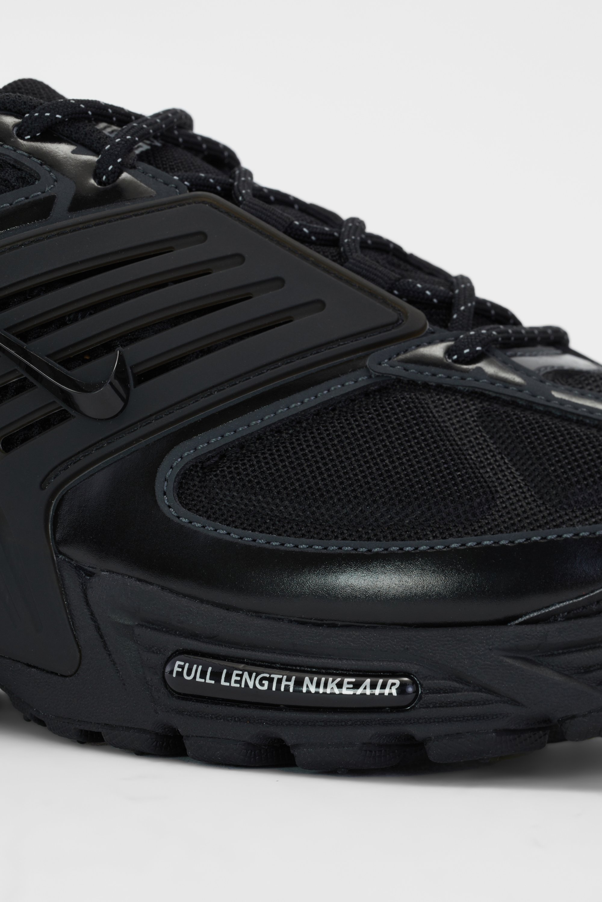 Close-up of a black Nike shoe featuring mesh and plastic details, with "FULL LENGTH NIKEAIR" label on the sole, highlighting its design.