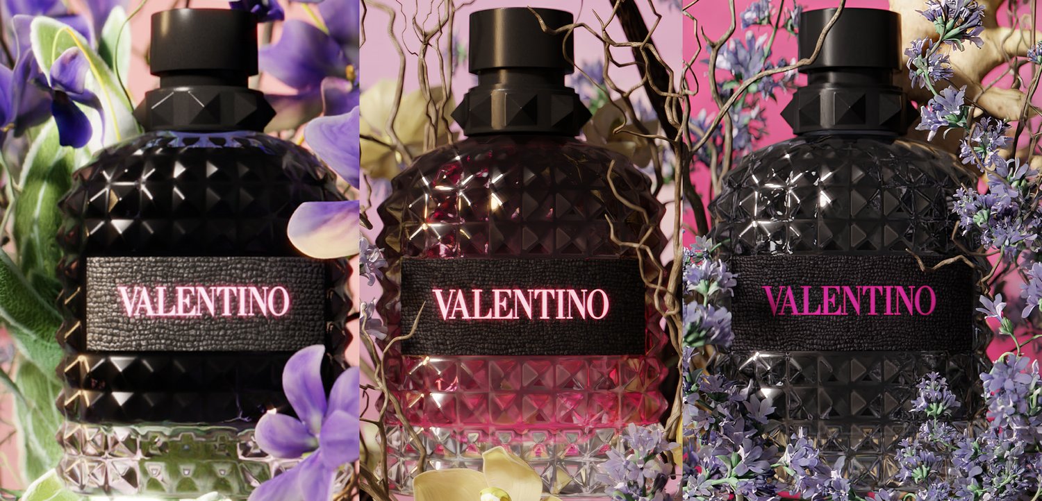 Three Valentino perfume bottles with textured black caps, surrounded by purple and yellow flowers against a soft pink background.