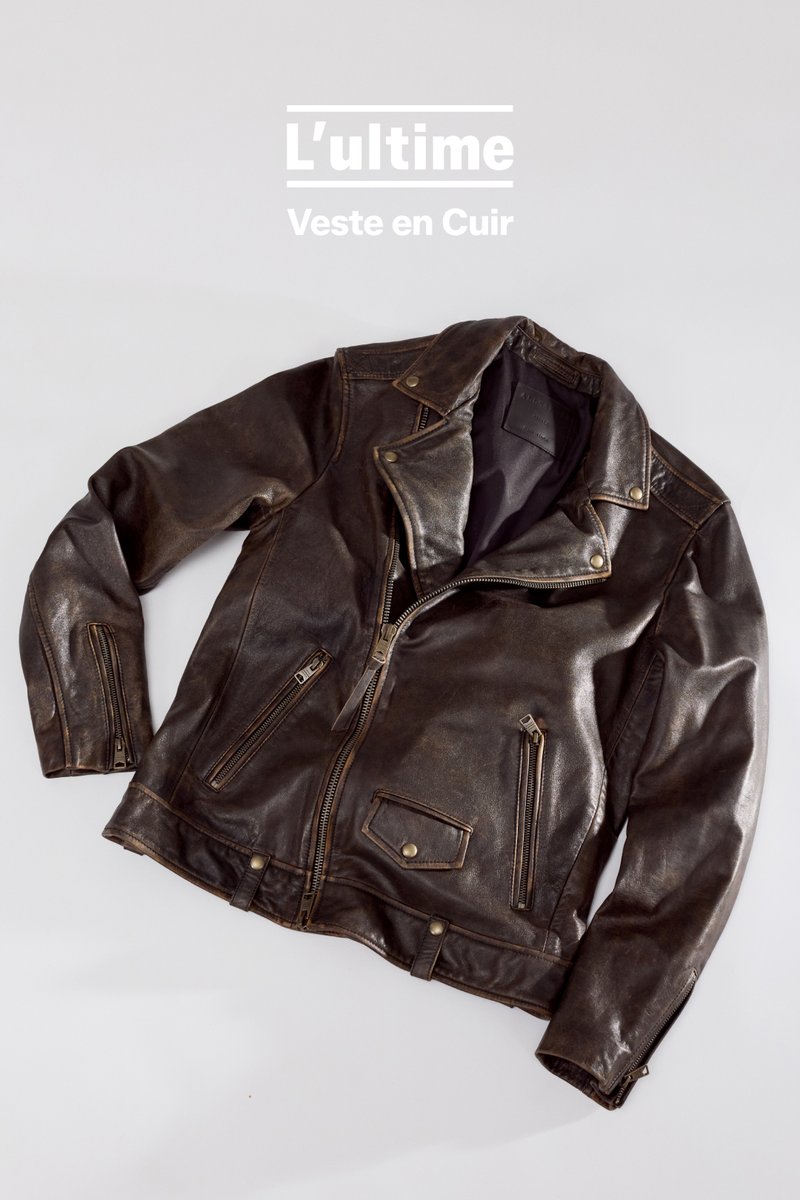 Veste de moto en cuir marron avec une finition texturée. Les caractéristiques incluent un col cranté, plusieurs poches zippées et des accents en métal.