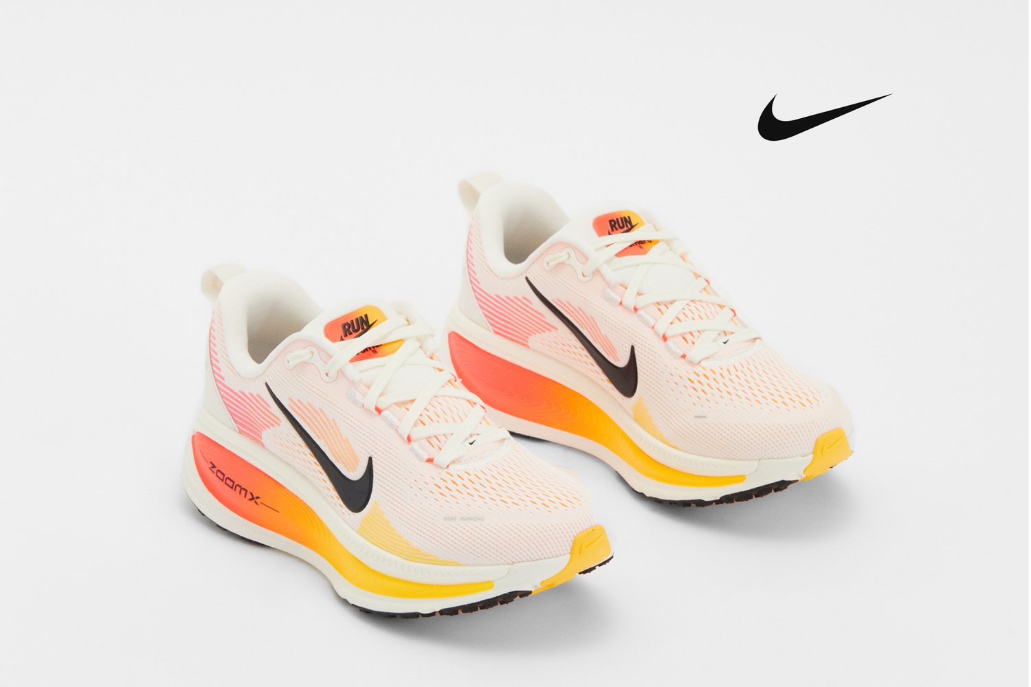 Zapatillas de running ligeras con un diseño en blanco y rosa, que presentan un swoosh negro de Nike y una suela amarilla vibrante. Aptas para actividades atléticas.