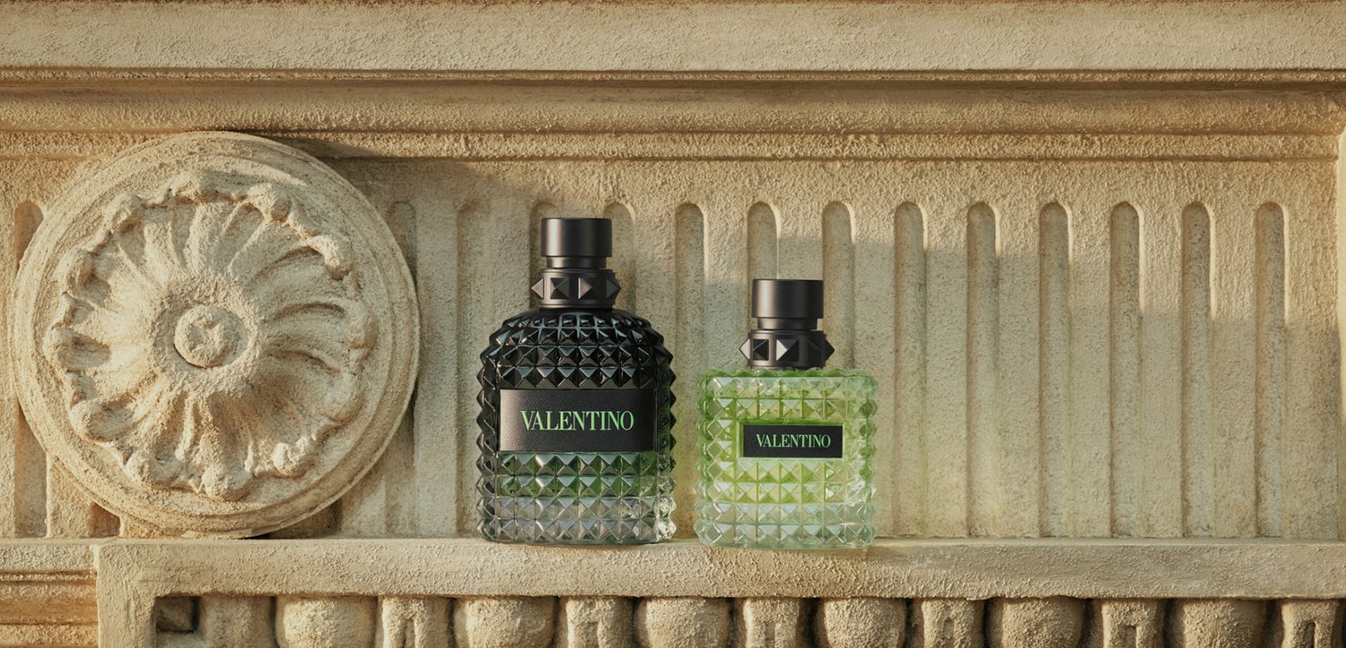 Twee gestructureerde Valentino parfumflesjes, één donker- en één lichtgroen, tentoongesteld op een decoratieve stenen plank met bloemmotief.