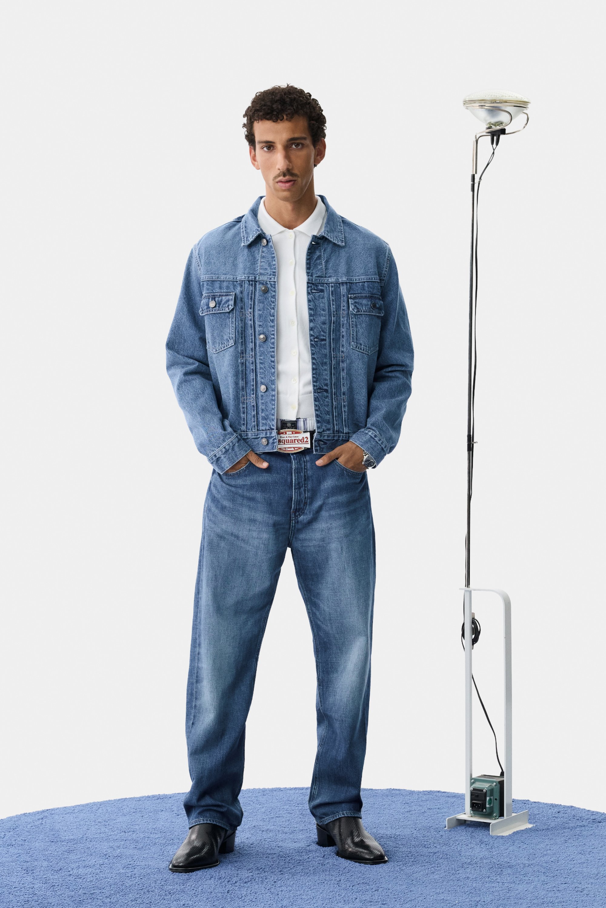 Denimjack met een lichte blauwe wassing en jeans, voorzien van voorzakken en een knoopsluiting. Zwarte enkellaarzen completeren de outfit.