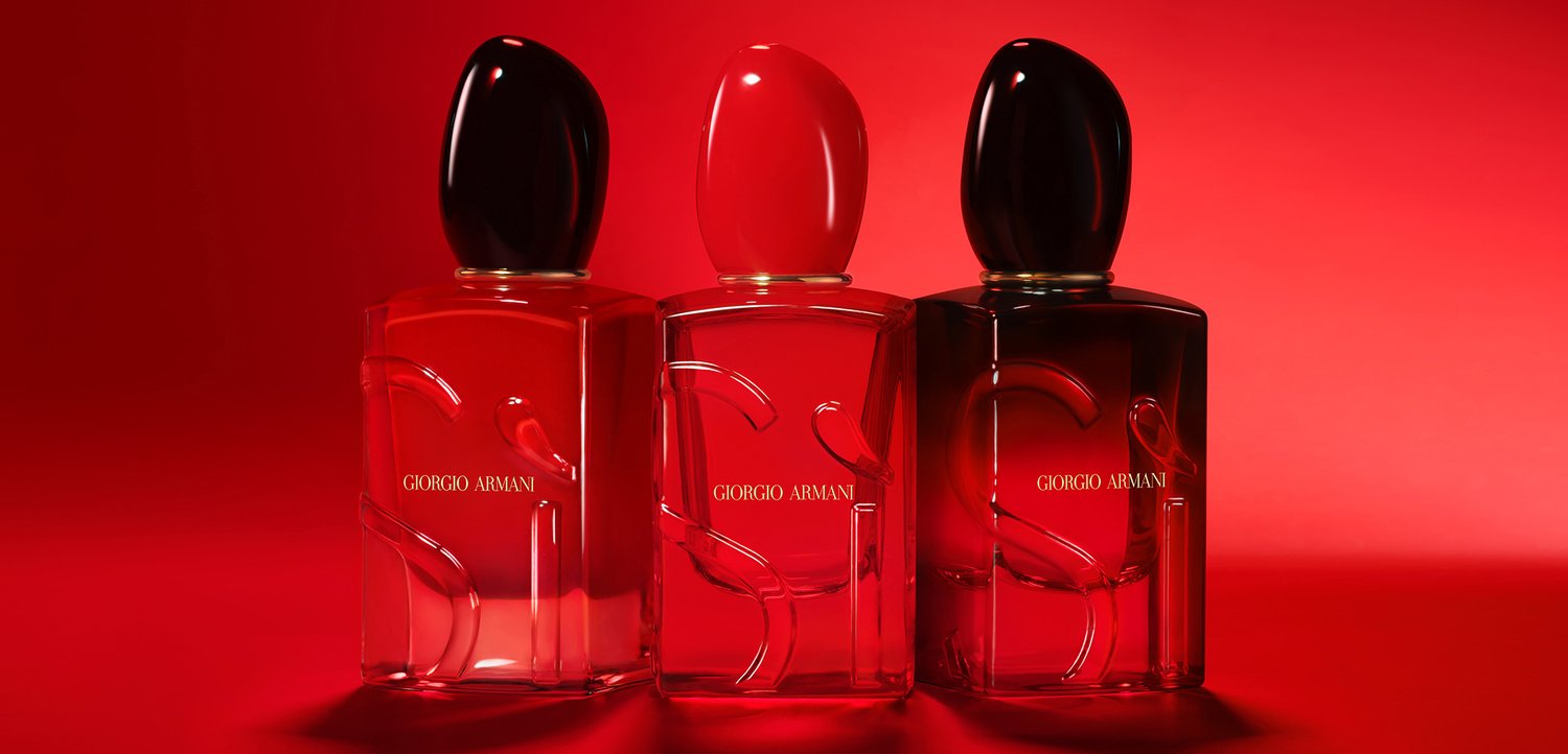 Drei Glasparfümflaschen von Giorgio Armani mit sanften Konturen und runden Kappen in Schwarz, Rot und transparenten Farbtönen vor einem roten Hintergrund.