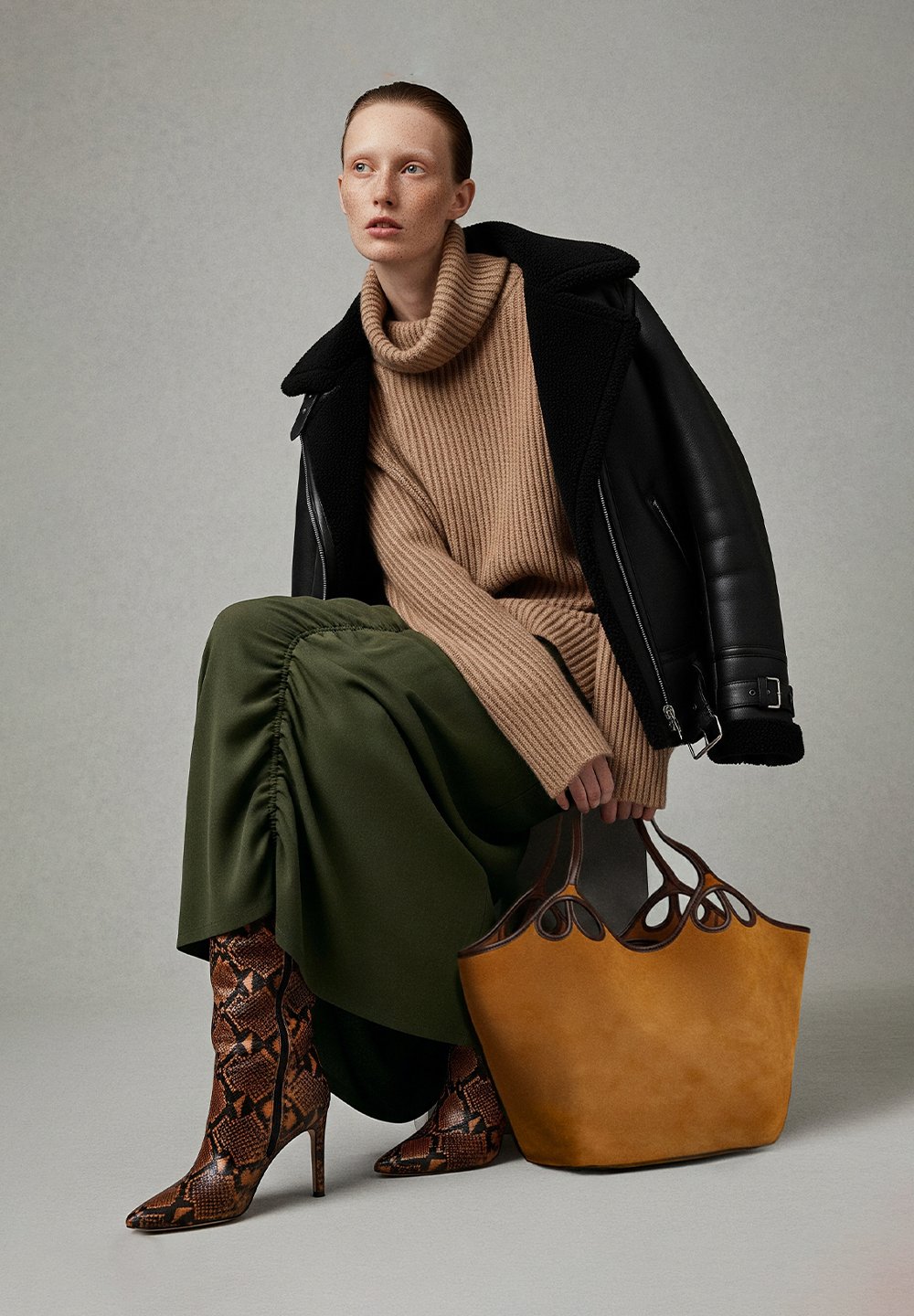 Beige ribbed turtleneck jumper, olive green gathered skirt, brown snake print stilettos, and a structured tan handbag with cut-out details.