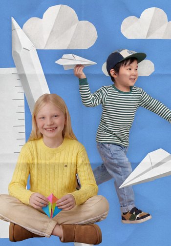 Ragazzo sorridente con maglietta a righe lancia un aereo di carta mentre una ragazza seduta con maglione giallo tiene un origami colorato su sfondo blu con nuvole.