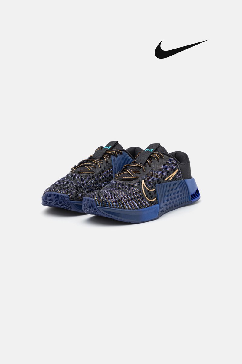 Blauwe en zwarte sport schoenen hebben een gestructureerd mesh ontwerp, een ronde neus en veters, met een prominent Nike-logo.