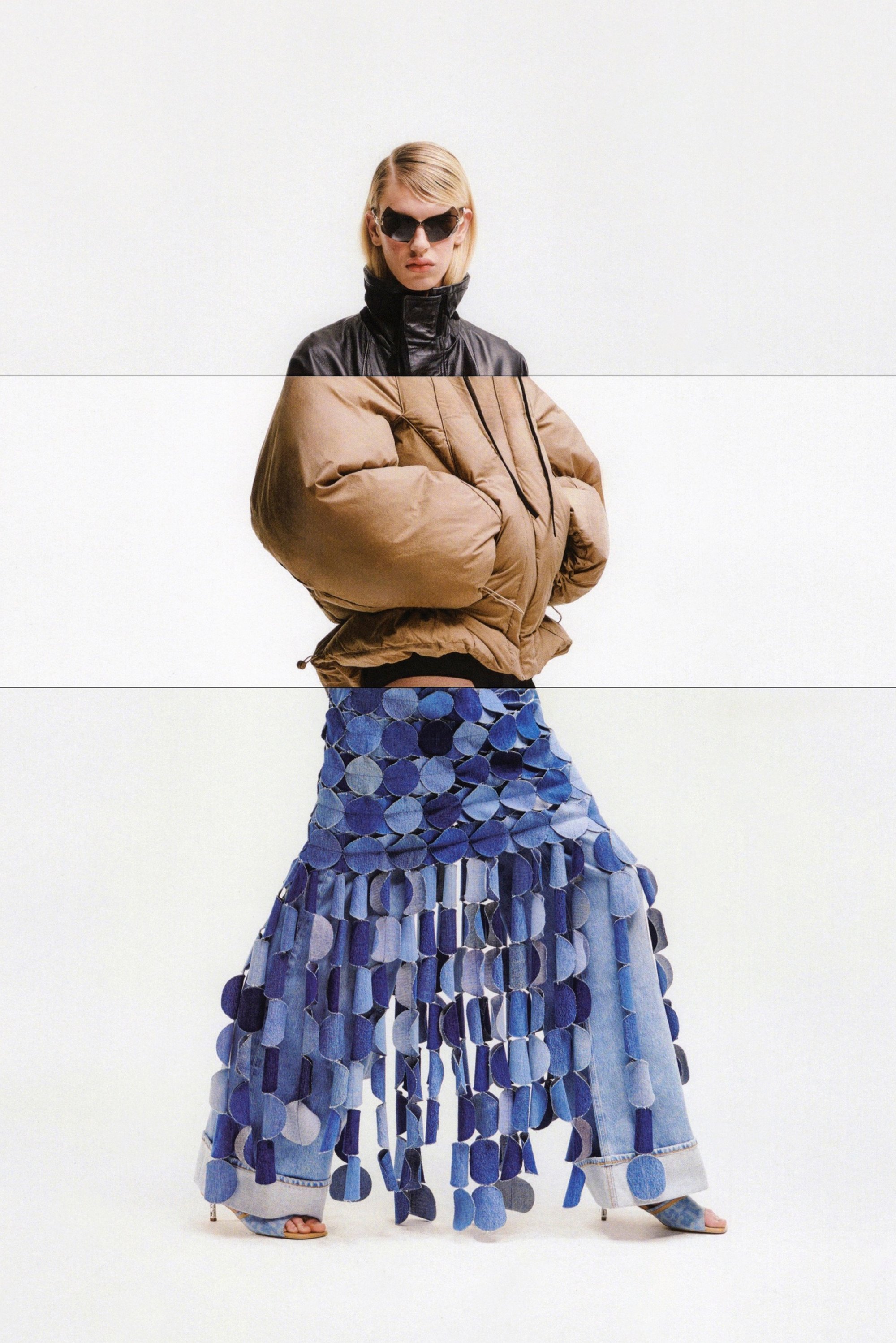 Una modelo lleva una chaqueta acolchada marrón de gran tamaño y una falda de mezclilla con capas y flecos, completando el look con unas gafas de sol oscuras.