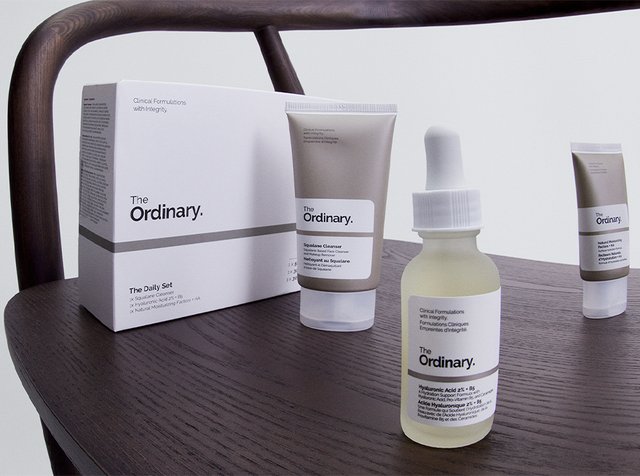 Hautpflegeprodukte von The Ordinary auf einer Holzoberfläche präsentiert, darunter ein Set mit Box und drei Tuben: Squalan-Reiniger, feuchtigkeitsspendendes Serum und Feuchtigkeitscreme.