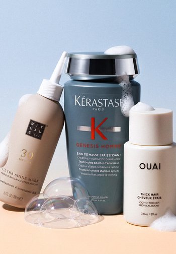 Trois produits de soin capillaire avec mousse et bulles : masque Rituals Ultra Shine, shampooing Kérastase Genesis Homme, et après-shampoing Ouai Thick Hair.