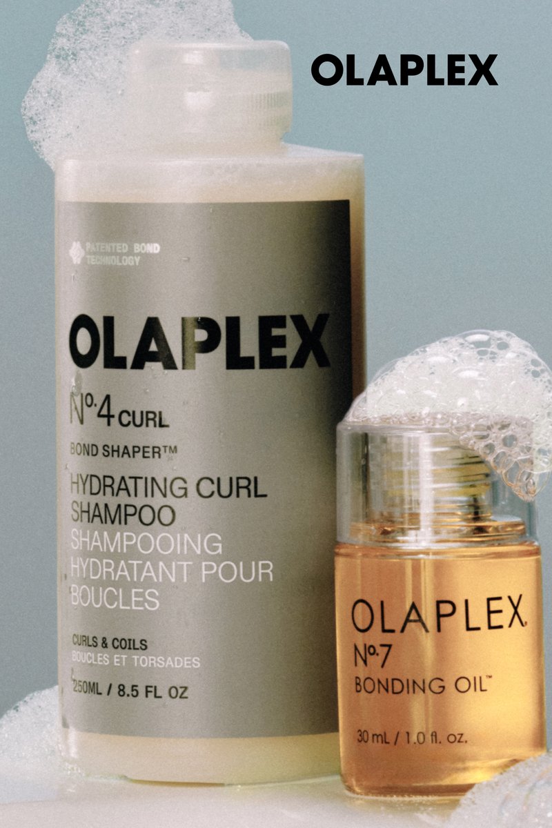 Olaplex No. 4 Curl Hydrating Curl Shampoo und No. 7 Bonding Oil Flaschen mit Schaum auf hellblauem Hintergrund.