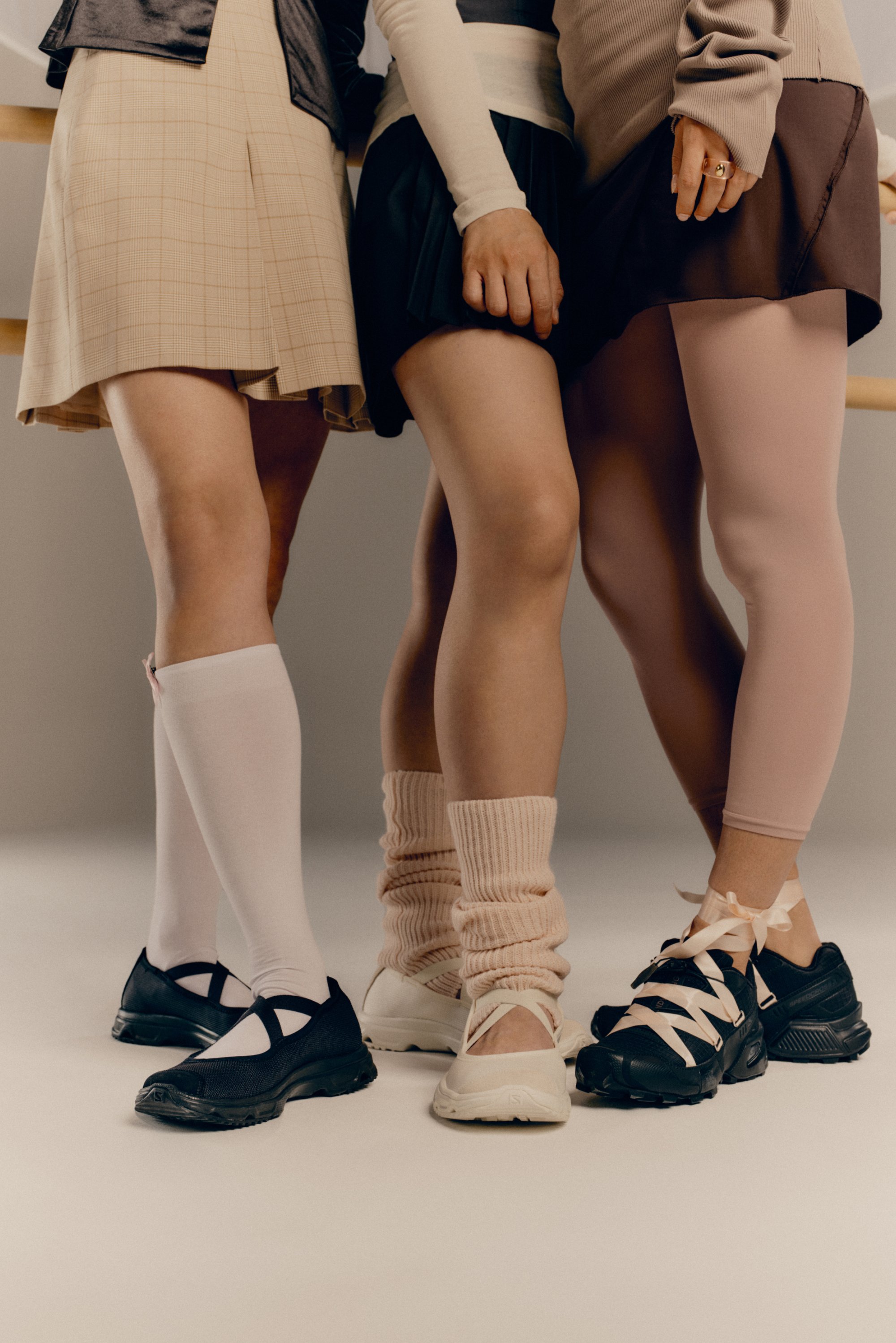 Drie paar benen in verschillende stijlen kleding en schoeisel zijn dicht bij elkaar gepositioneerd, met de nadruk op verschillende sokken en schoenen.