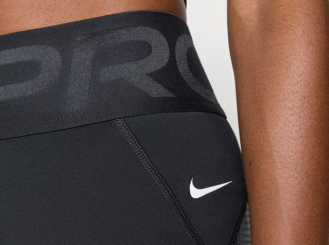 Primo piano di leggings atletici neri con una fascia larga in vita che mostra la parola parziale "PRO" e un logo Nike swoosh bianco.