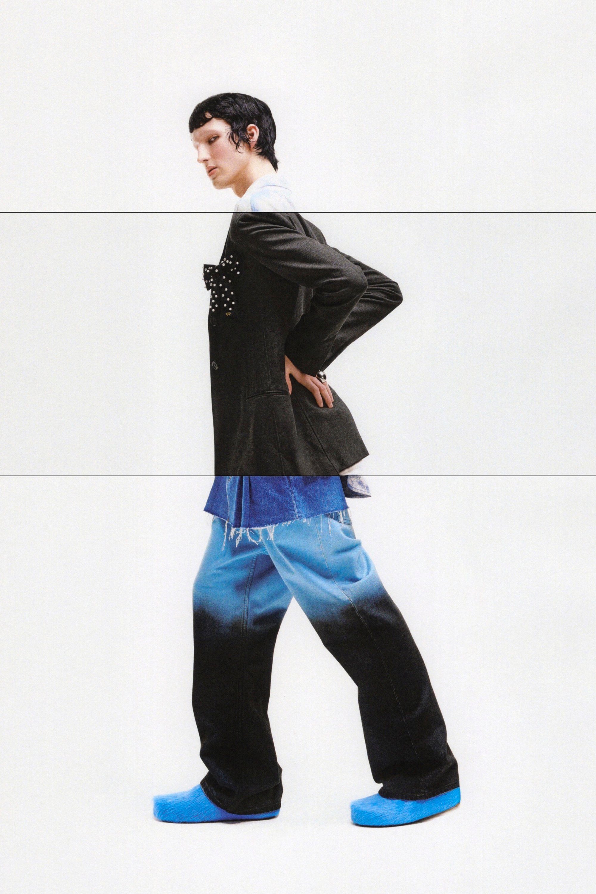 Una modelo con una elegante chaqueta gris con un detalle de lazo, superpuesta a una blusa de mezclilla azul y pantalones, posa con unos zapatos de color azul brillante.