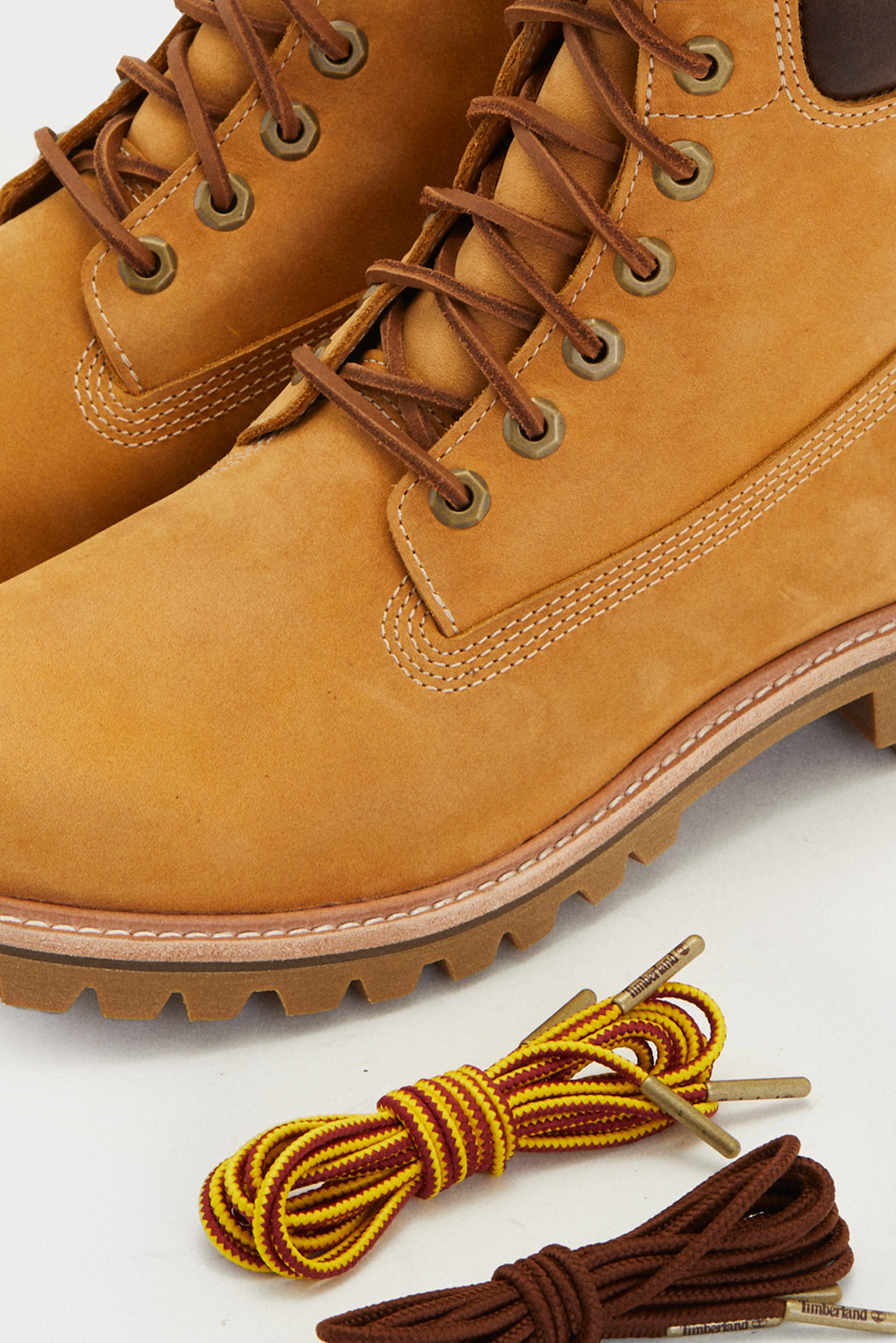 Brown suede boots featuring metallic eyelets and brown laces. Comes with two pairs of laces: one with yellow and red stripes, and another in solid brown.