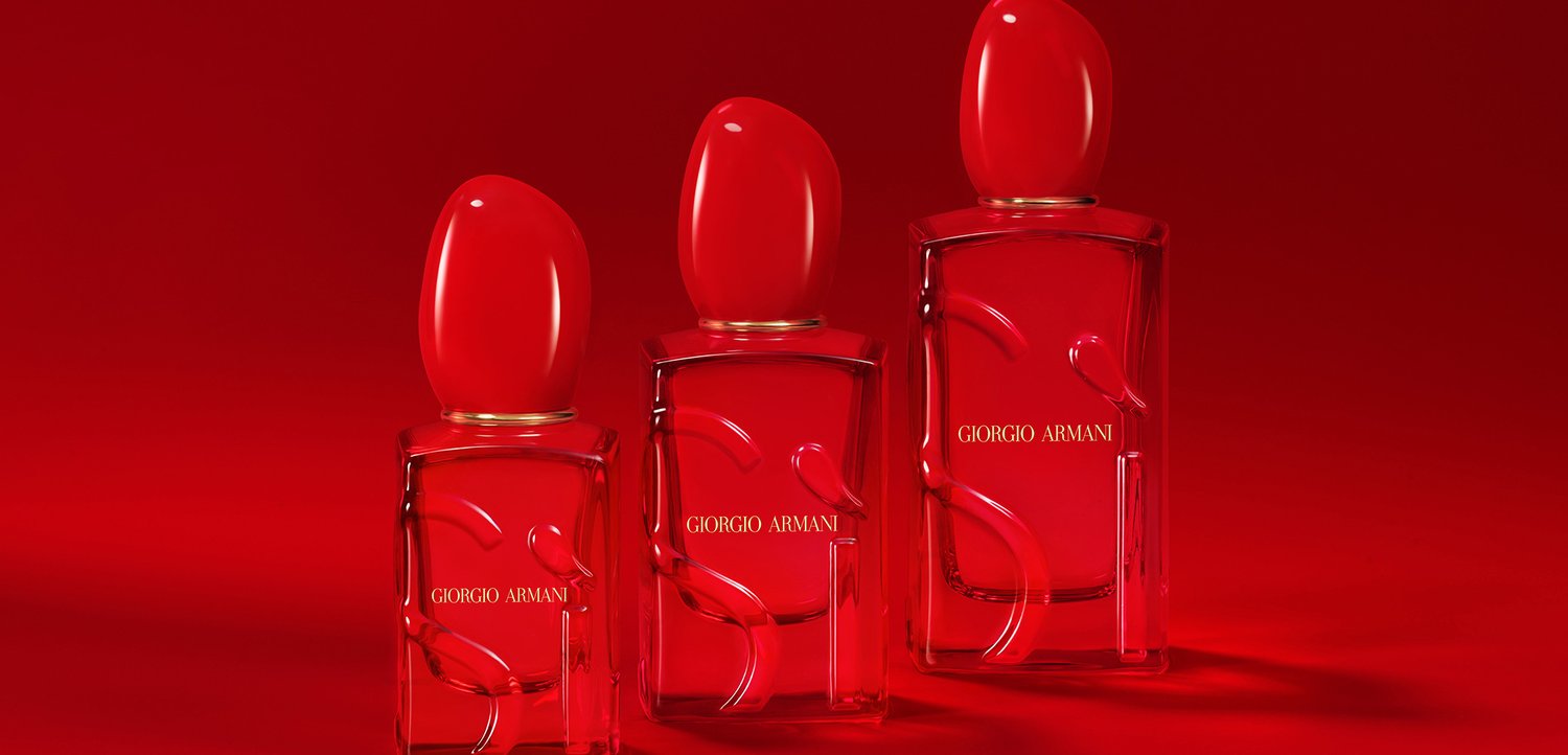 Drei Glasparfümflaschen mit roten, ovalen Kappen, die erhabene Designs und die goldene Markenbezeichnung "Giorgio Armani" aufweisen, vor einem roten Hintergrund.