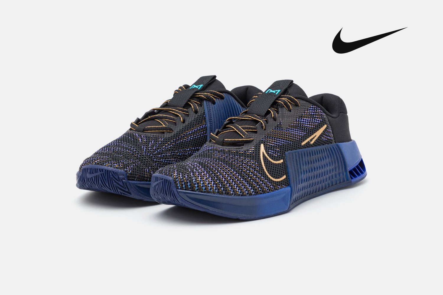 Zapatillas deportivas Nike en negro y azul con un upper texturizado y detalles dorados, exhibidas lado a lado sobre un fondo blanco.