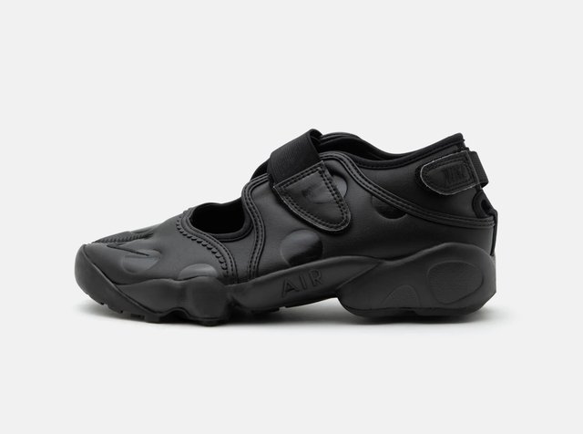 Chaussure de sport noire avec zones ouvertes, sangles ajustables et semelle épaisse marquée de "AIR" sur fond blanc.