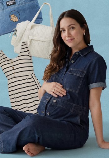 Raskaana oleva nainen farkkuhaalarissa istuu paljain jaloin, hymyillen, raidallinen mekko, valkoinen tikattu laukku ja sininen Moschino-vauvalaukku sinisellä taustalla.