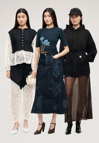 Drei Frauen stehen nebeneinander und tragen stilvolle Outfits: ein weißes Spitzenensemble mit schwarzer Überlagerung, ein blaues florales Oberteil mit dunklem Rock und ein schwarzer Hoodie mit durchsichtigem Rock.