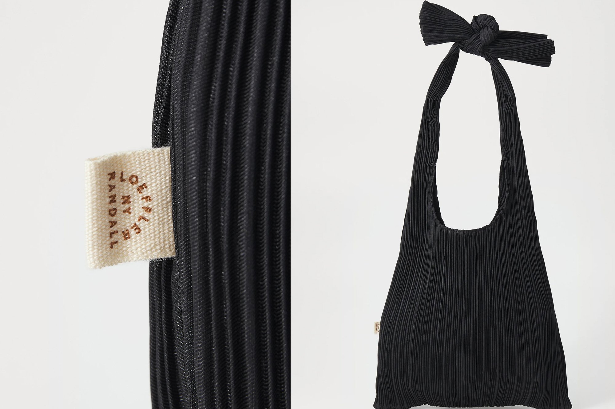 Bolsa tote negra con pliegues y un asa anudada, que presenta una tela texturizada y una etiqueta tejida en el lateral. Diseño simple y funcional.