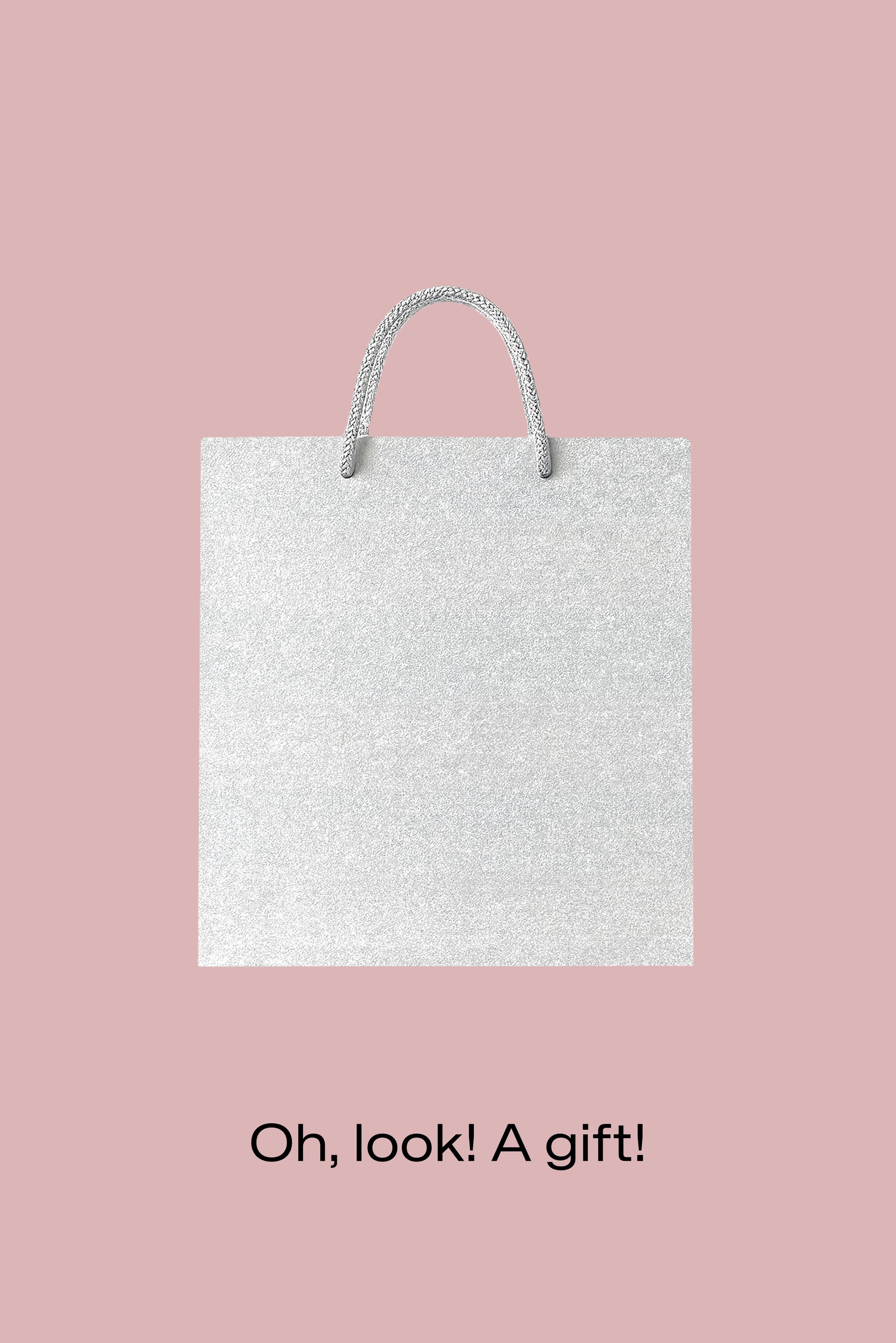 Borsa regalo argentata con superficie testurizzata e glitterata. Dotata di manici robusti in carta intrecciata. Lo sfondo è di un rosa tenue e smorzato.