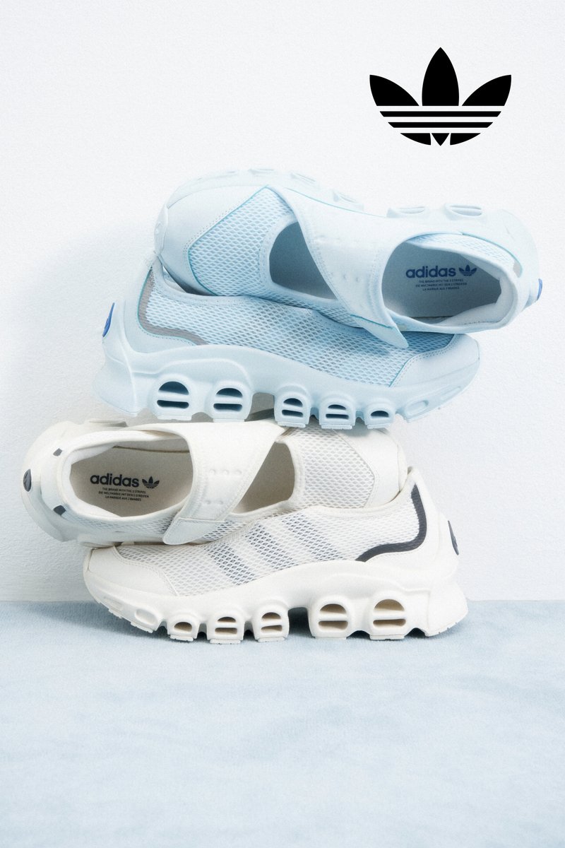 Stacked light blue and white Adidas sneakers display unique designs against a plain background, featuring the Adidas logo above.