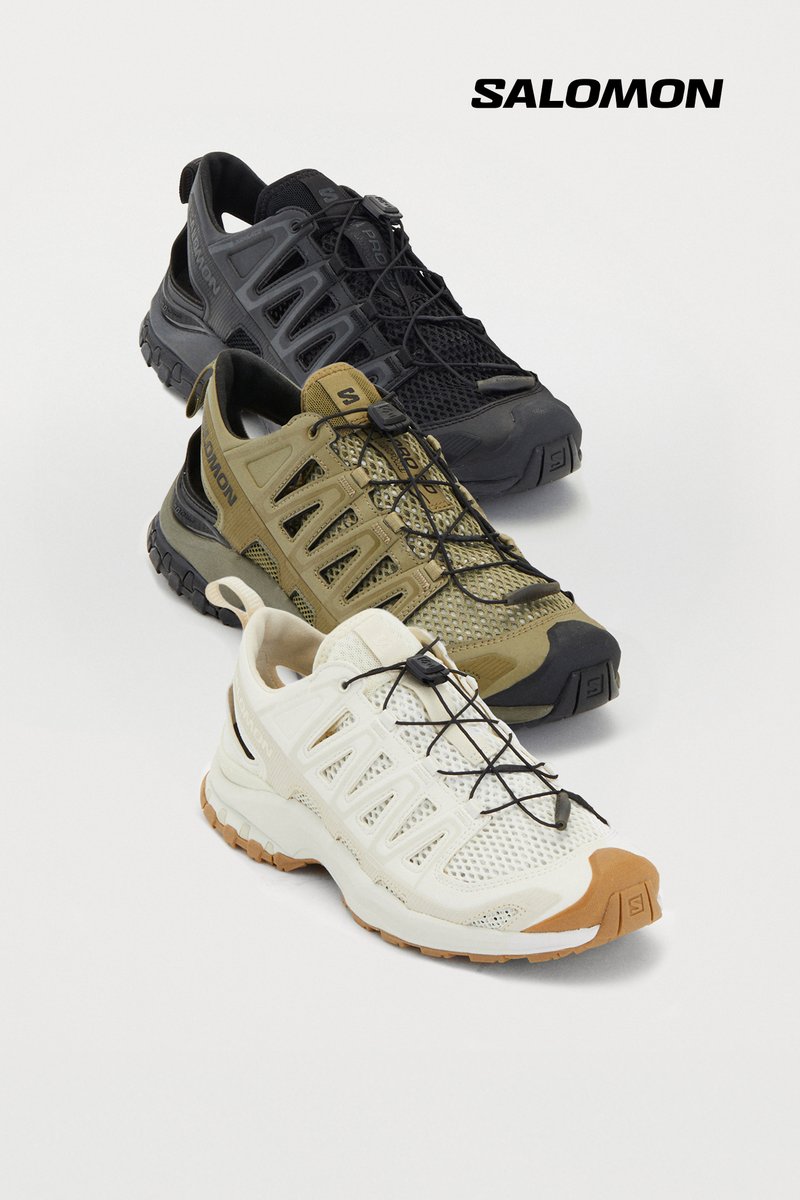Three pairs of Salomon shoes in black, olive green, and white, arranged in a stacked formation against a white background.