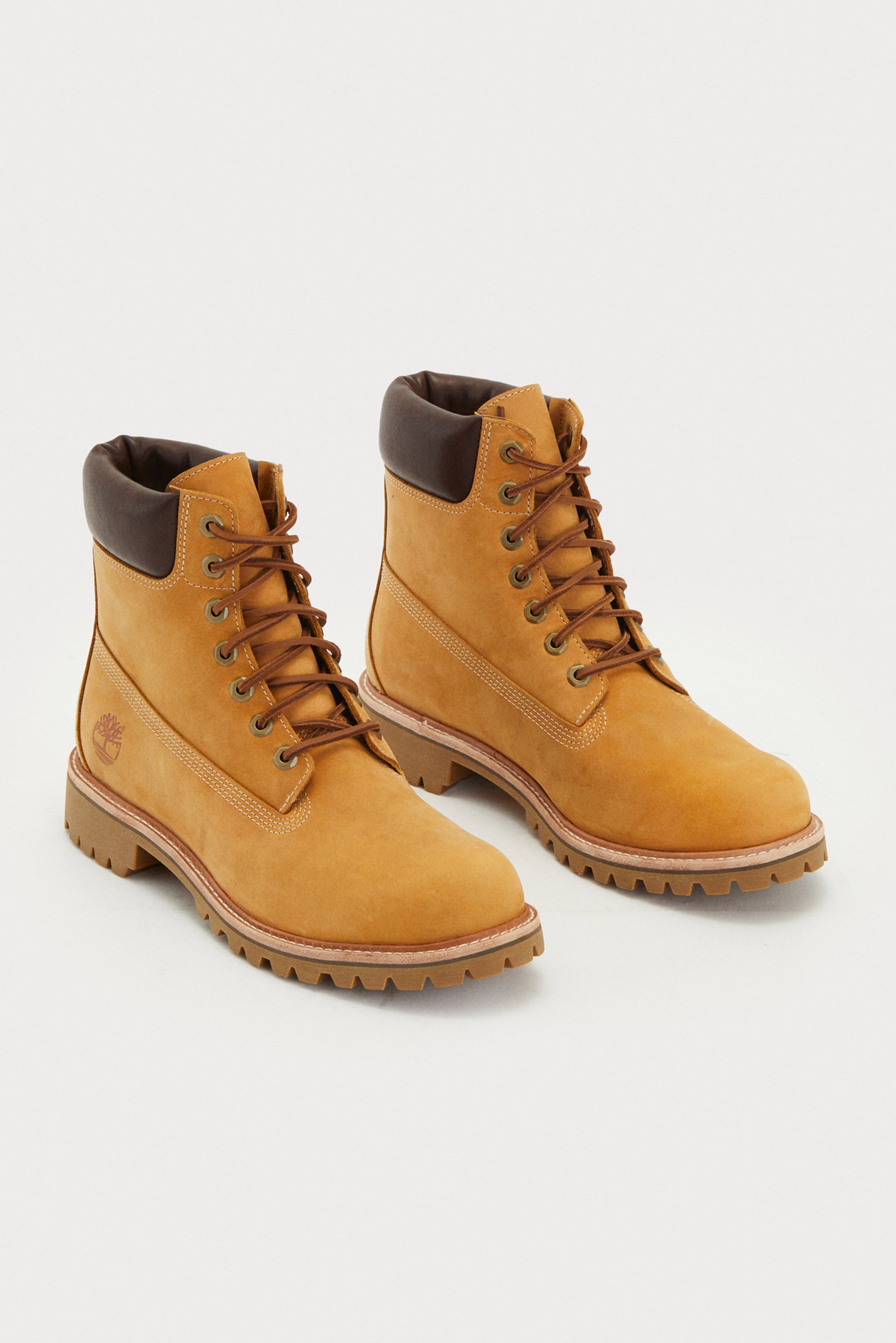 Tan leather boots featuring a brown padded collar, round toe, and contrasting laces. They have a rugged sole with a defined tread pattern and the Timberland logo displayed on the side.