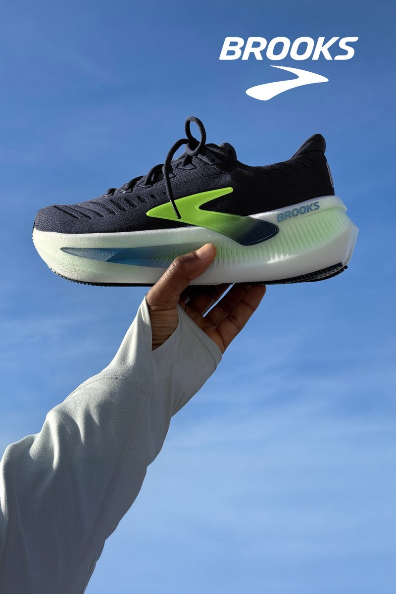 Zwart hardloopschoen met groene accenten en een lichtgrijze zool, voorzien van een gestructureerd mesh bovenwerk en verlengde hiel.